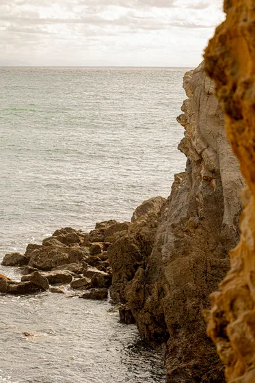 A sandstone cliff face cut hard against a flat pale sea